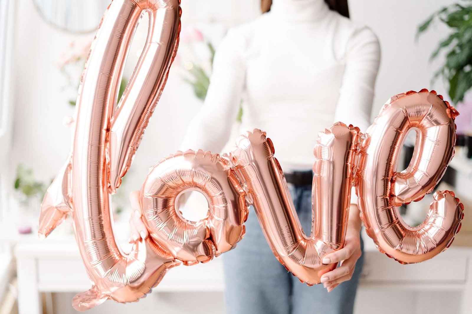 Woman holding balloons spelling out the word love